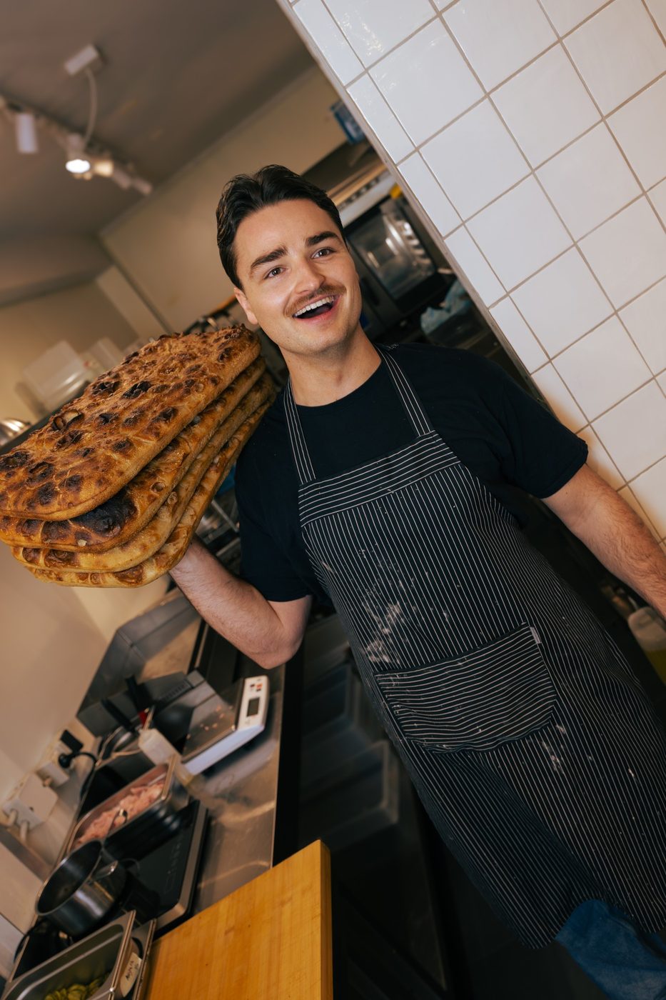A Rosèl cook carrying fresh focaccia out of the kitchen