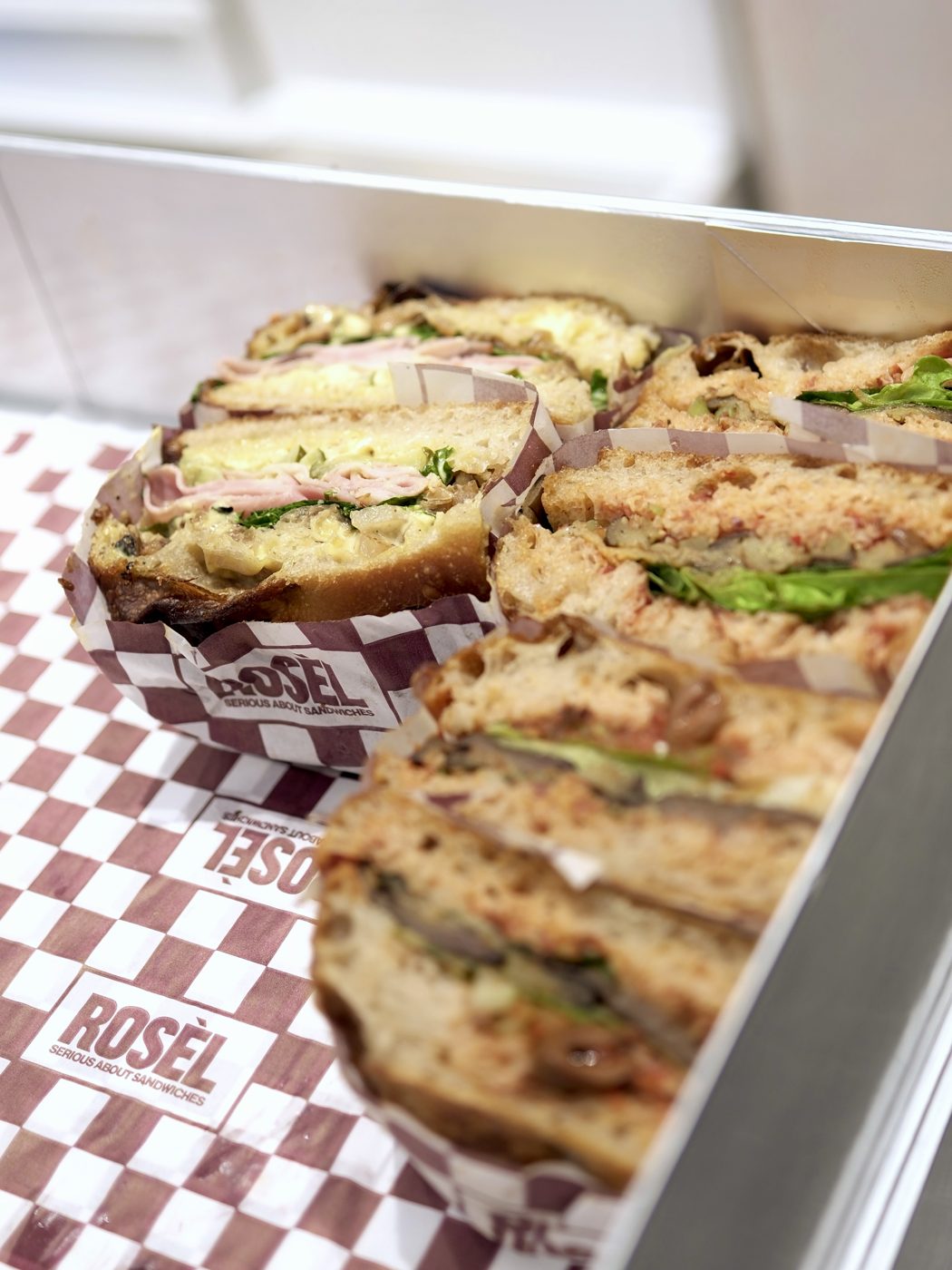 Rosèl sandwiches in checkered paper, packed in a catering box