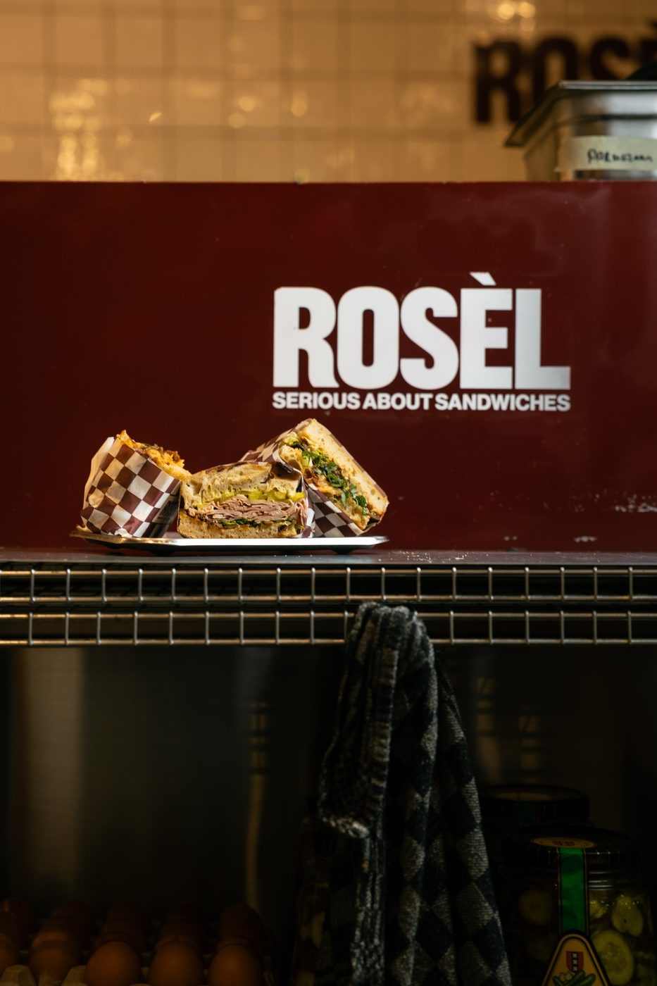 Sandwiches on the counter under the Rosèl sign
