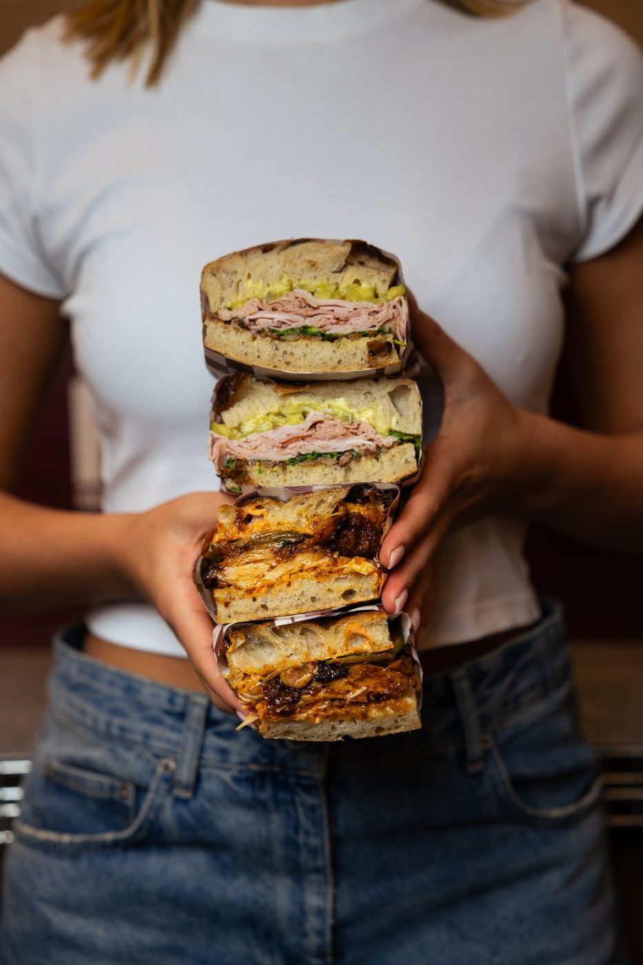 Four Rosèl sandwiches stacked in two hands