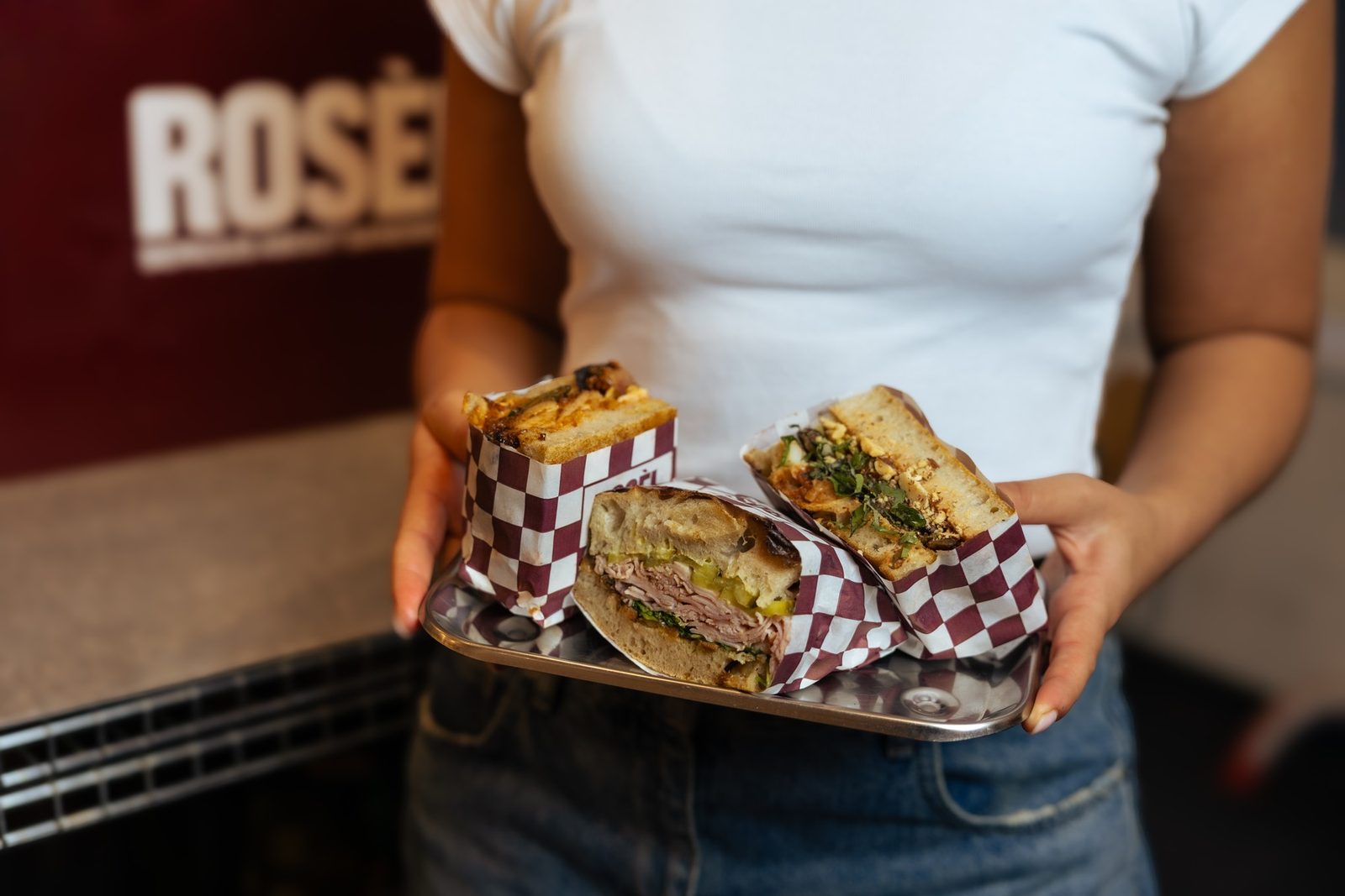 A tray of warm Rosèl sandwiches in checkered paper